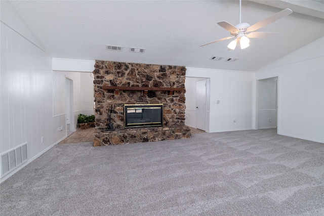 unfurnished living room with a fireplace, a textured ceiling, ceiling fan, carpet flooring, and vaulted ceiling