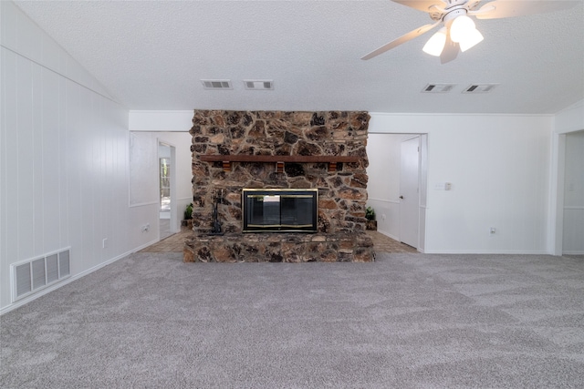 unfurnished living room with a textured ceiling, carpet, ceiling fan, and a stone fireplace