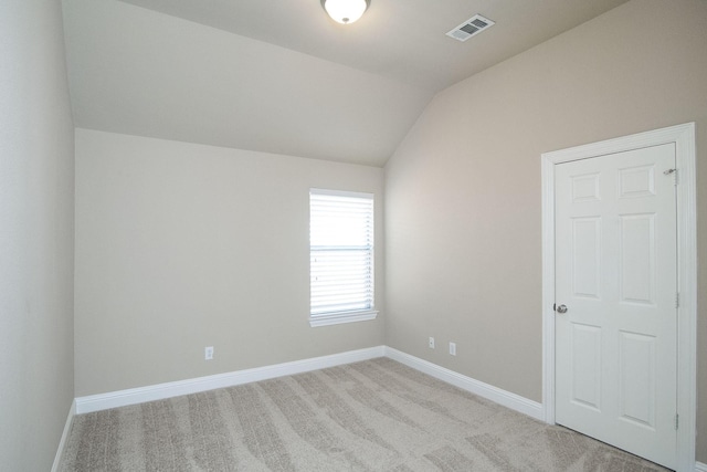 carpeted empty room featuring vaulted ceiling