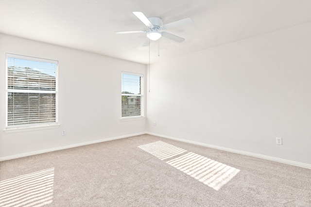 carpeted spare room featuring plenty of natural light and ceiling fan