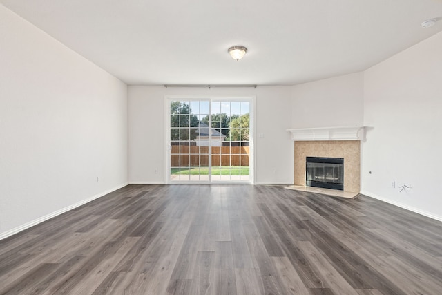 unfurnished living room featuring a tiled fireplace and dark hardwood / wood-style floors