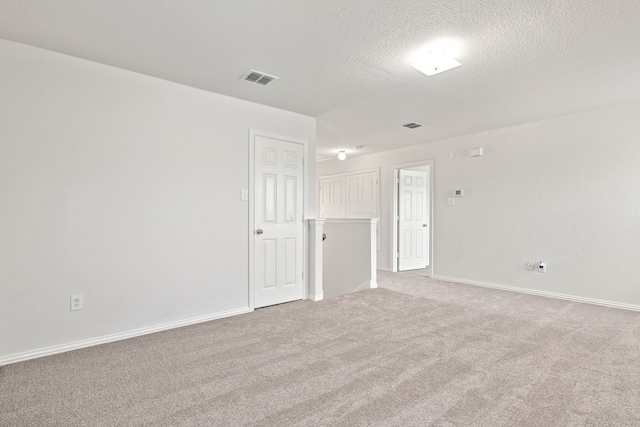 unfurnished room with a textured ceiling and light colored carpet