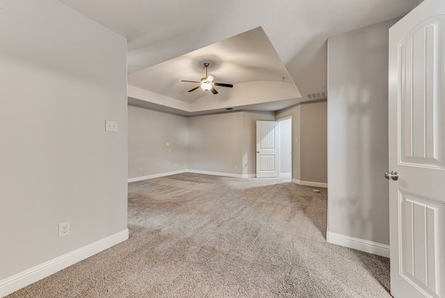 carpeted spare room with ceiling fan and a raised ceiling