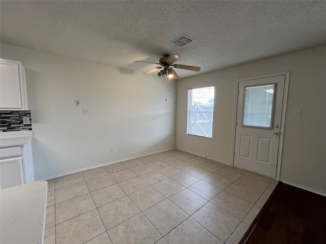 unfurnished dining area with a textured ceiling, light tile patterned floors, and ceiling fan