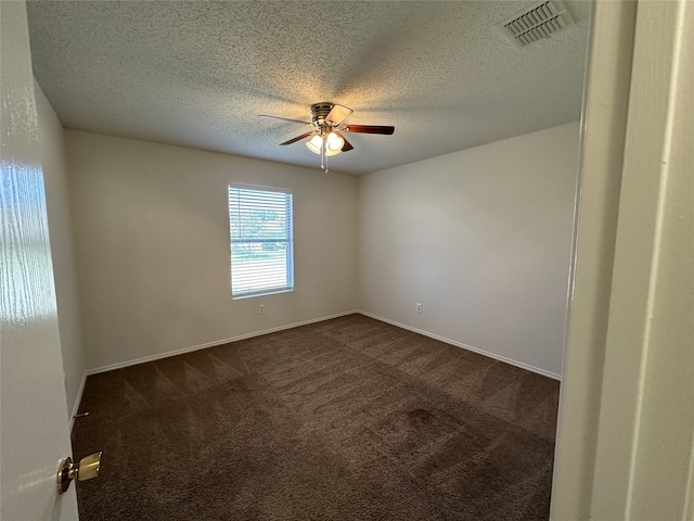 spare room with ceiling fan, a textured ceiling, and dark colored carpet