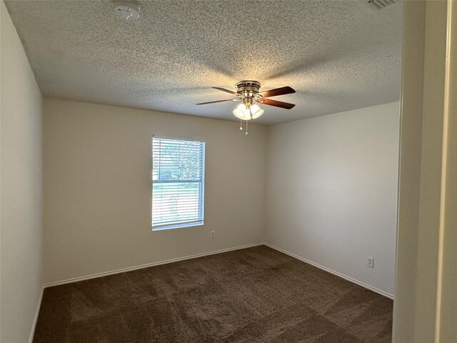 spare room with ceiling fan, a textured ceiling, and dark colored carpet