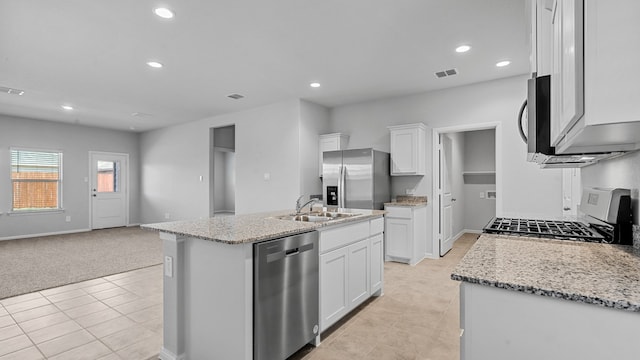 kitchen with a kitchen island with sink, light carpet, stainless steel appliances, and white cabinets