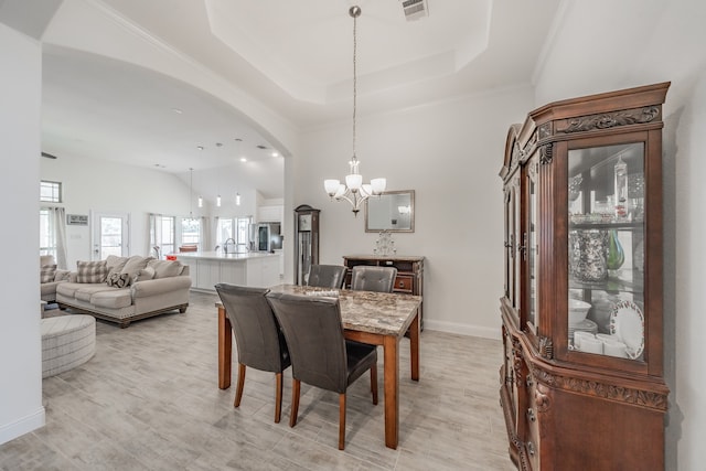 dining area with a tray ceiling, crown molding, and a chandelier