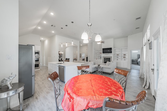 dining area with lofted ceiling, ceiling fan with notable chandelier, light hardwood / wood-style floors, and sink