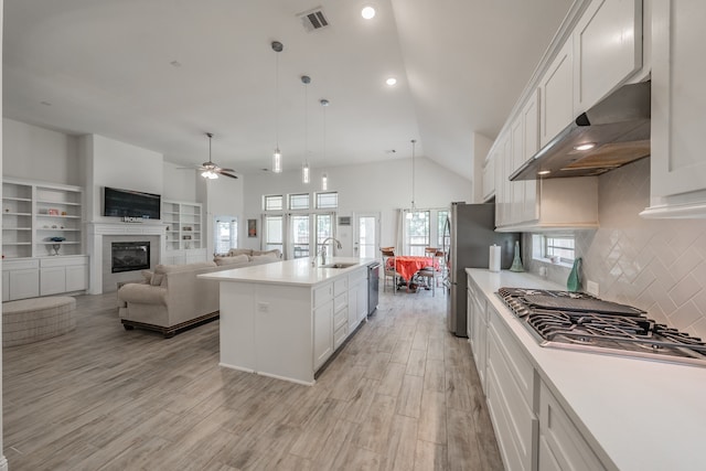 kitchen featuring lofted ceiling, ceiling fan with notable chandelier, white cabinetry, and a kitchen island with sink