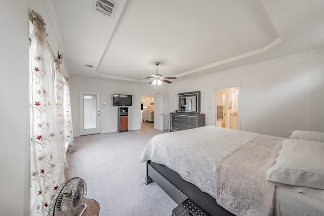 bedroom with ensuite bath, light colored carpet, a tray ceiling, and ceiling fan