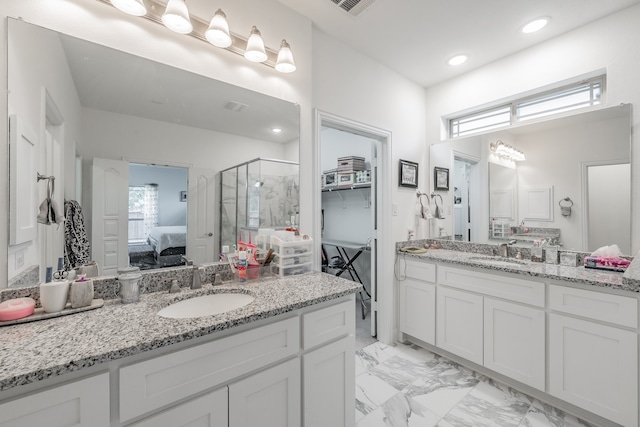 bathroom featuring a shower with shower door and vanity