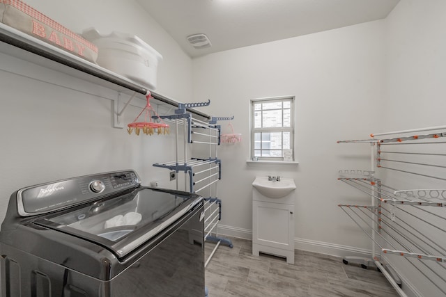 laundry room with light hardwood / wood-style floors, sink, and washer / clothes dryer