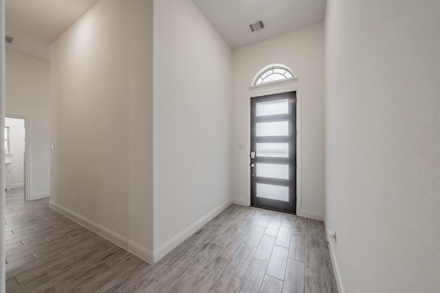 foyer entrance with high vaulted ceiling and wood-type flooring