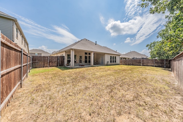 back of house featuring a lawn and a patio