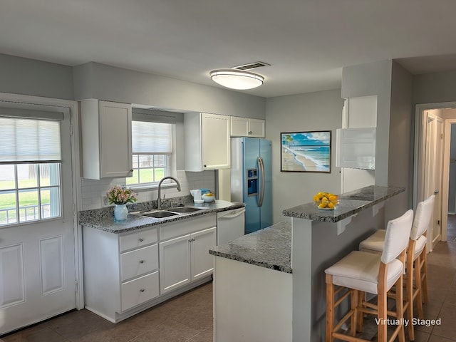 kitchen with dishwasher, sink, stainless steel fridge, white cabinets, and decorative backsplash