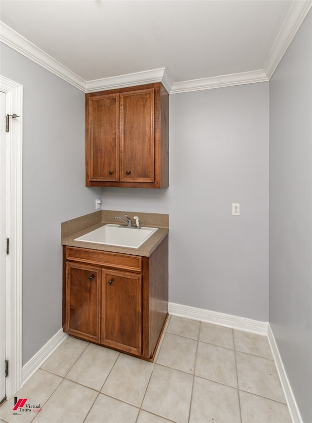 laundry area featuring ornamental molding, sink, and light tile patterned floors