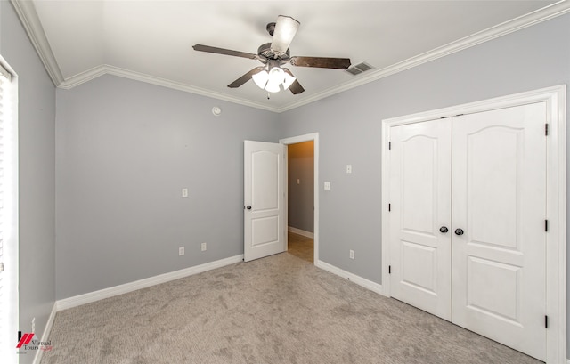 unfurnished bedroom with ornamental molding, light carpet, ceiling fan, and a closet