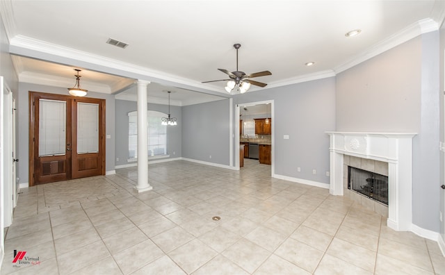 unfurnished living room with ceiling fan with notable chandelier, crown molding, decorative columns, and a tiled fireplace