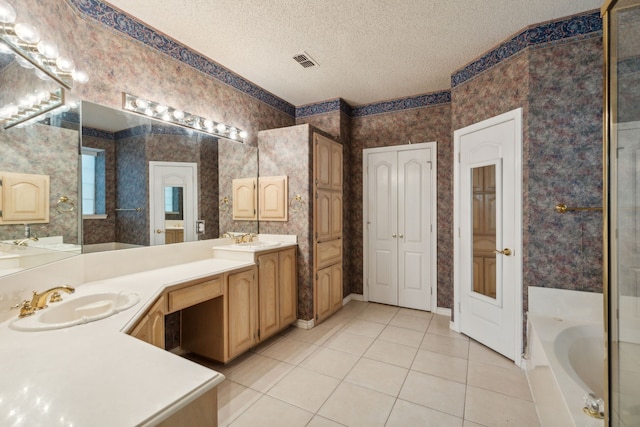 bathroom featuring a textured ceiling, vanity, a bath, and tile patterned floors