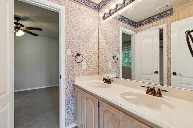 bathroom with ceiling fan, a textured ceiling, and vanity