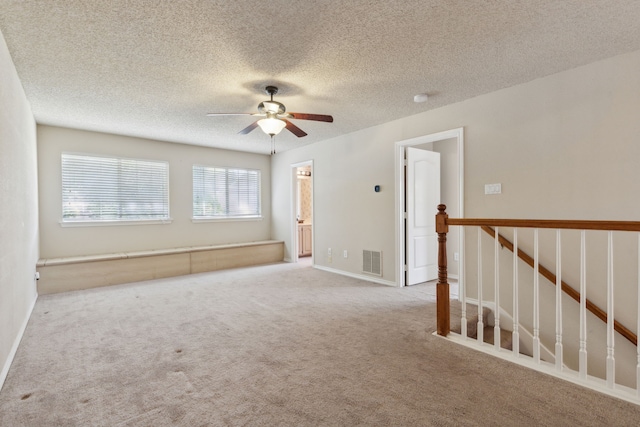 unfurnished room featuring a textured ceiling, ceiling fan, and light colored carpet