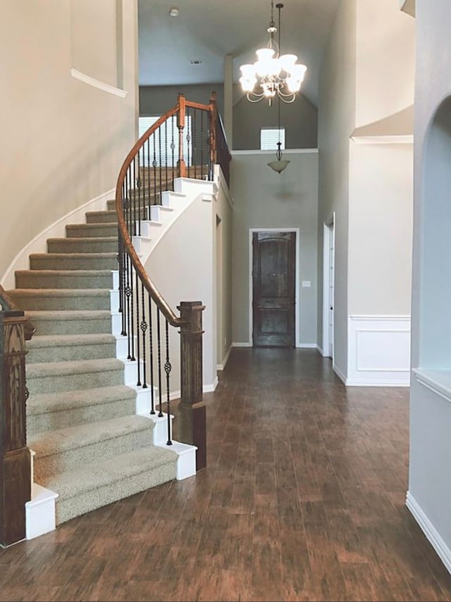 foyer entrance featuring dark wood-type flooring, a chandelier, and a towering ceiling