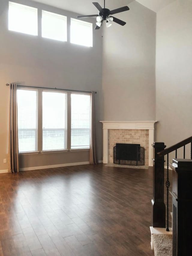 unfurnished living room with high vaulted ceiling, ceiling fan, dark wood-type flooring, and a fireplace