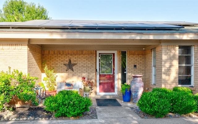 view of exterior entry with a porch and solar panels