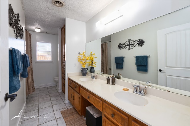 bathroom featuring toilet, a textured ceiling, vanity, and tile patterned floors