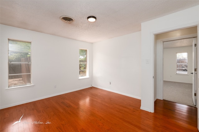 empty room featuring wood-type flooring and a textured ceiling