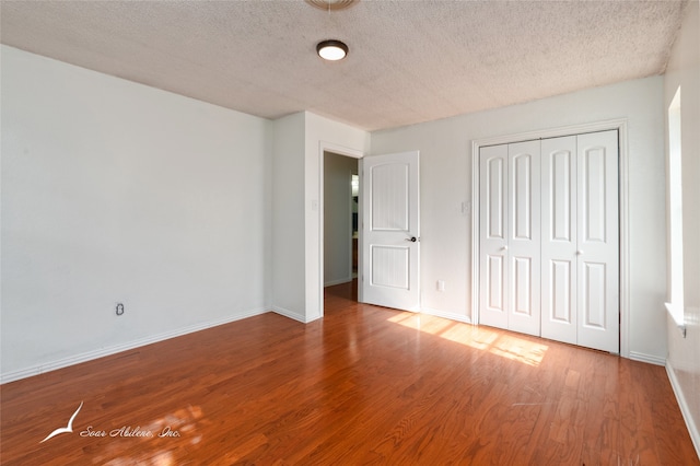 unfurnished bedroom with a textured ceiling, wood-type flooring, and a closet