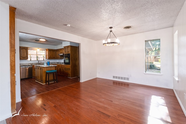 interior space with dark hardwood / wood-style floors, a wealth of natural light, pendant lighting, and a kitchen island