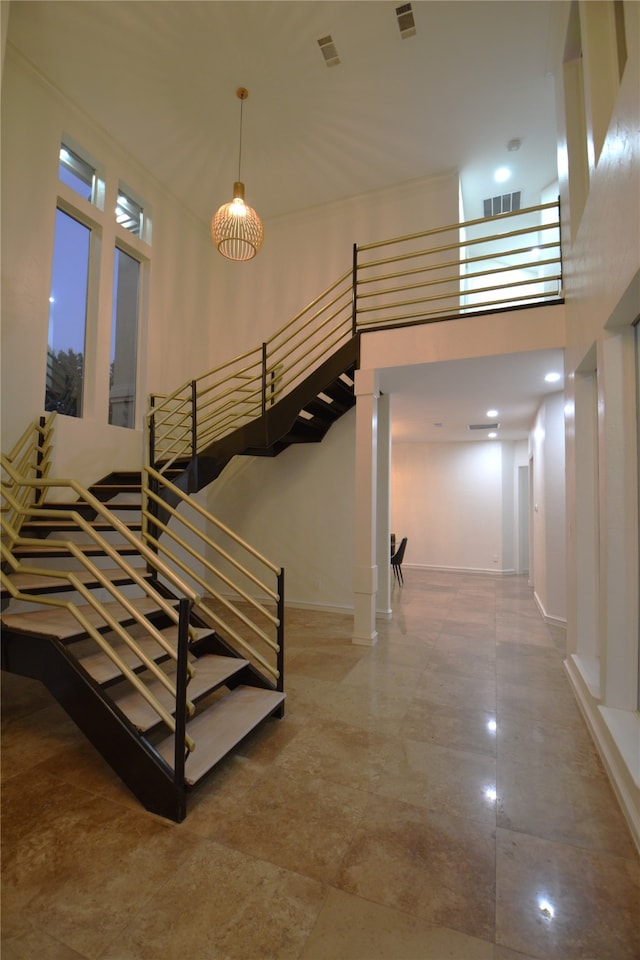 corridor featuring a towering ceiling and an inviting chandelier