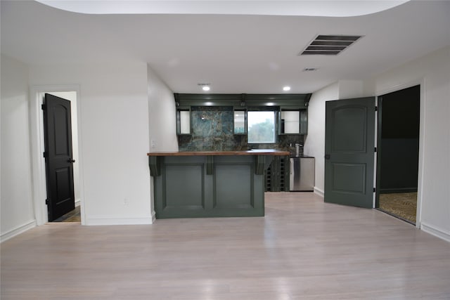 kitchen with backsplash, light hardwood / wood-style floors, kitchen peninsula, and a breakfast bar