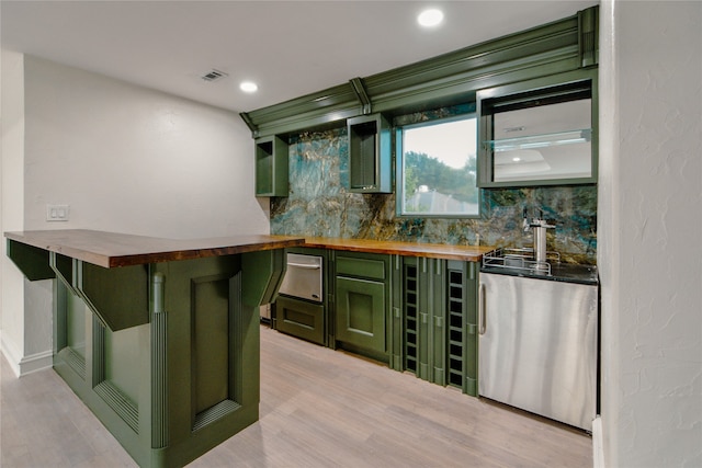 bar featuring light hardwood / wood-style flooring, butcher block counters, backsplash, and green cabinets