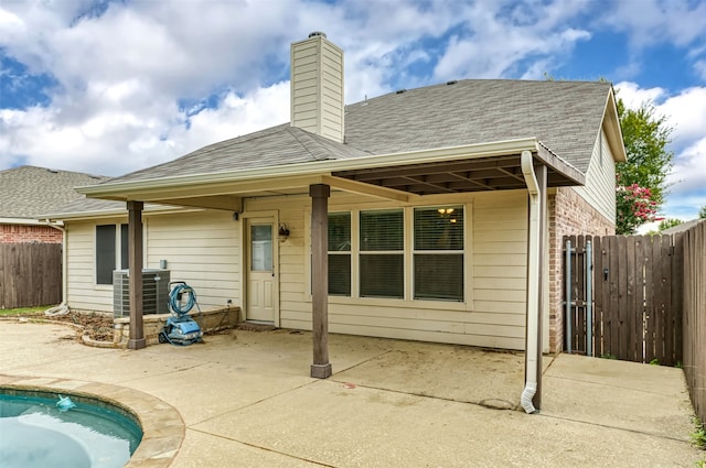 rear view of property with cooling unit and a patio