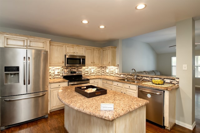 kitchen with lofted ceiling, light stone counters, sink, kitchen peninsula, and appliances with stainless steel finishes