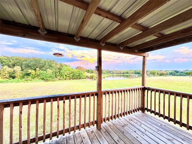 deck at dusk featuring a water view and a lawn