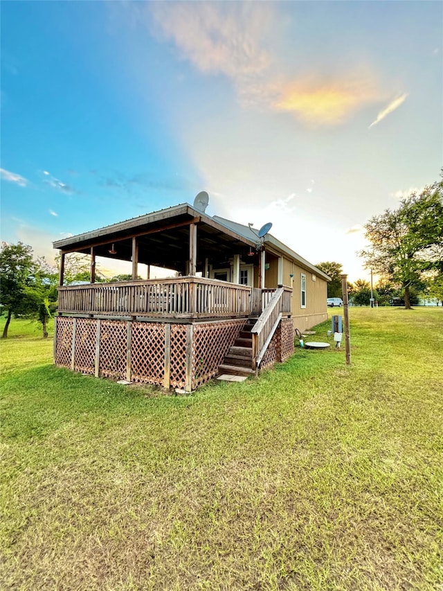 back house at dusk with a yard and a wooden deck