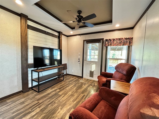 living room with ornamental molding, a raised ceiling, hardwood / wood-style floors, and ceiling fan