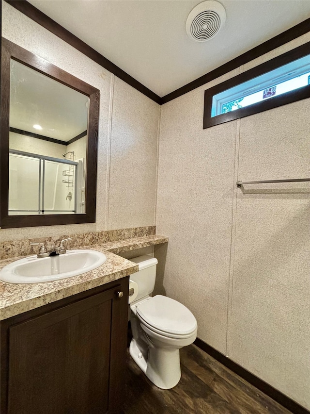 bathroom featuring toilet, a shower with door, ornamental molding, vanity, and wood-type flooring