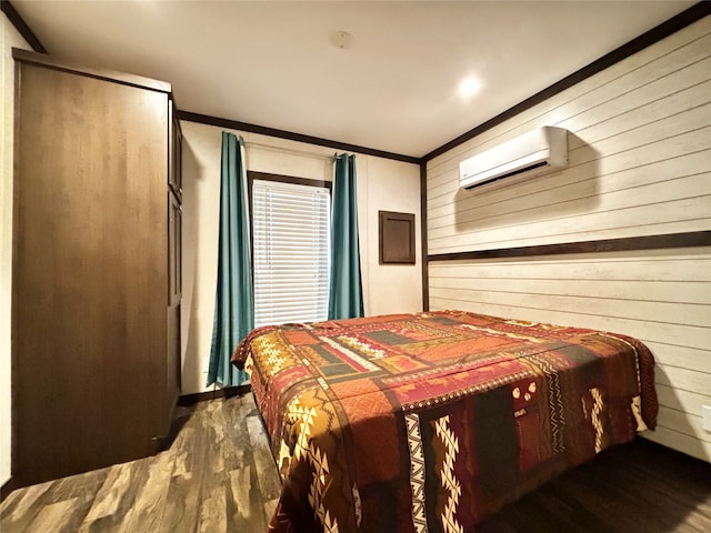 bedroom featuring a wall mounted AC, ornamental molding, and hardwood / wood-style floors