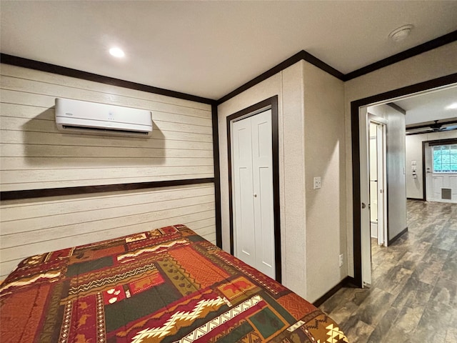 unfurnished bedroom featuring crown molding, dark hardwood / wood-style flooring, and a wall mounted air conditioner