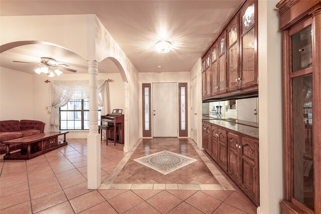 entryway featuring light tile patterned floors, ceiling fan, and decorative columns