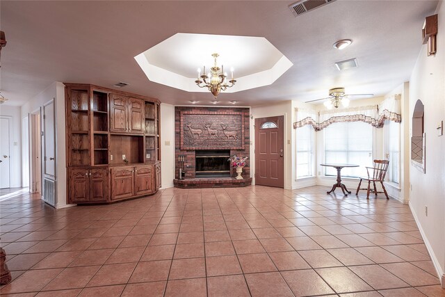 unfurnished living room with a fireplace, light tile patterned flooring, a raised ceiling, and ceiling fan with notable chandelier