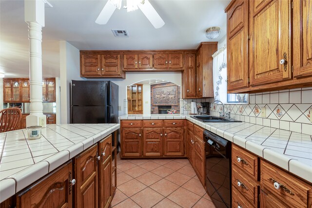 kitchen featuring tile counters, black appliances, sink, backsplash, and light tile patterned floors