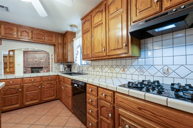 kitchen with tile counters, white gas cooktop, black dishwasher, sink, and decorative backsplash