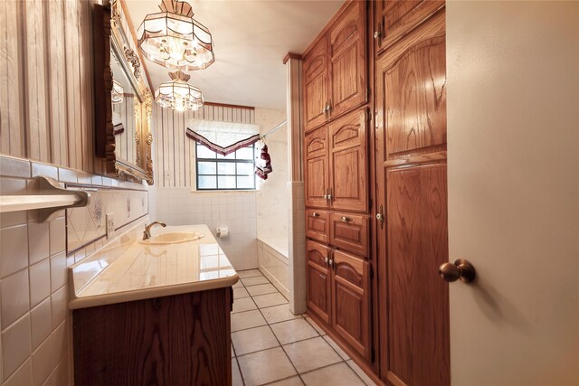 bathroom with a washtub, tile walls, tile patterned floors, vanity, and an inviting chandelier