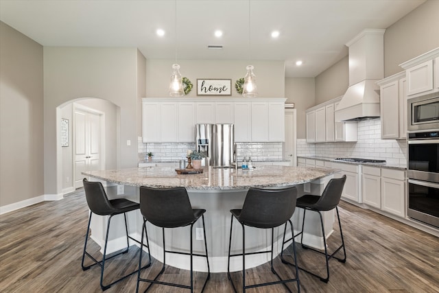 kitchen featuring white cabinetry, appliances with stainless steel finishes, wood-type flooring, and a center island with sink